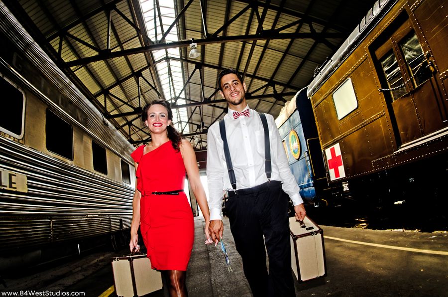 Vintage retro wedding engagement shoot in a train yard. Red dress, bow tie, birdcage black veil, vintage suitcases. South Florida Weddings by www.84WestStudios.com (954)236-9000.