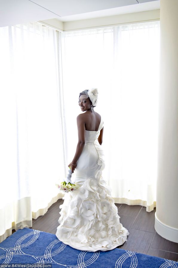 Beautiful white wedding gown, one shoulder, romantic and frilly large blossoms adding a sweet look of ruffles. Elegant and beautiful with a white birdcage veil and bold hair flower with crystal brooch accent. South Florida weddings by www.84WestStudios.com (954)236-9000.